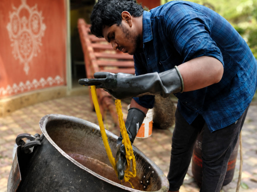 An artisan lifting yarn from a natural dye vat
