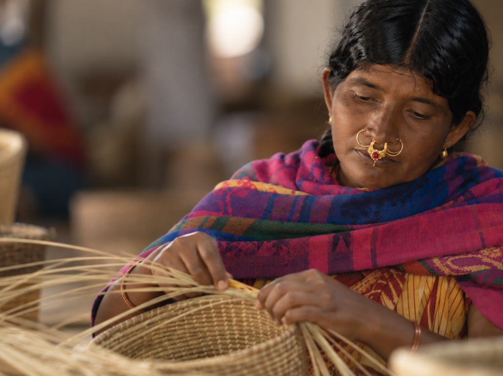 A woman coiling golden grass into a basket