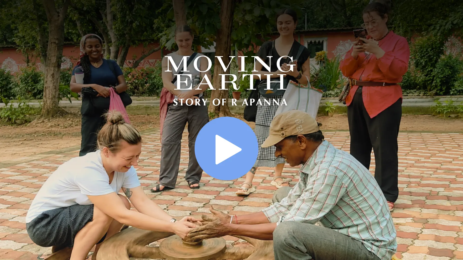 Community Teacher R. Apanna shaping clay on a potter's wheel with visiting students watching — Moving Earth film