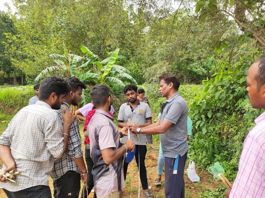 Facilitator showing bamboo measuring sticks to students on a field walk