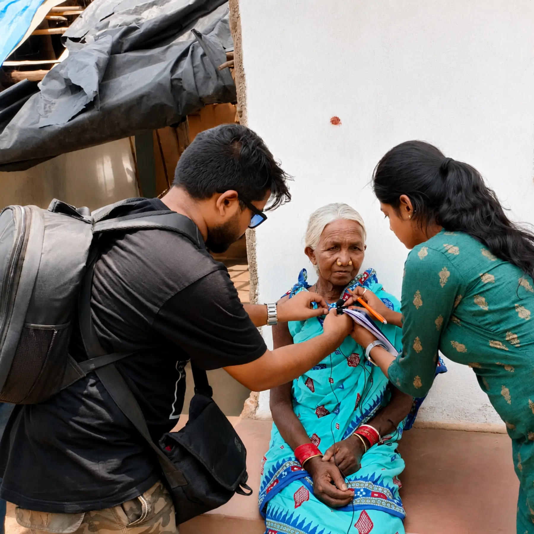 Field team recording an elder woman's account outside her home