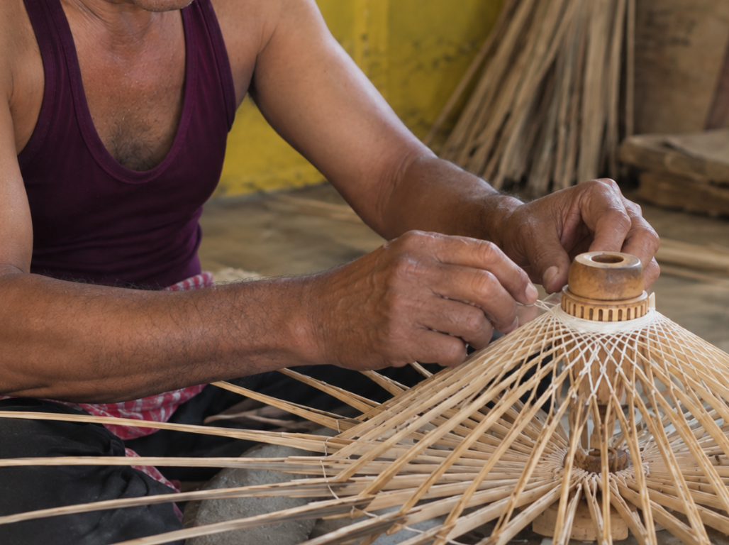An artisan weaving the bamboo frame of an umbrella by hand