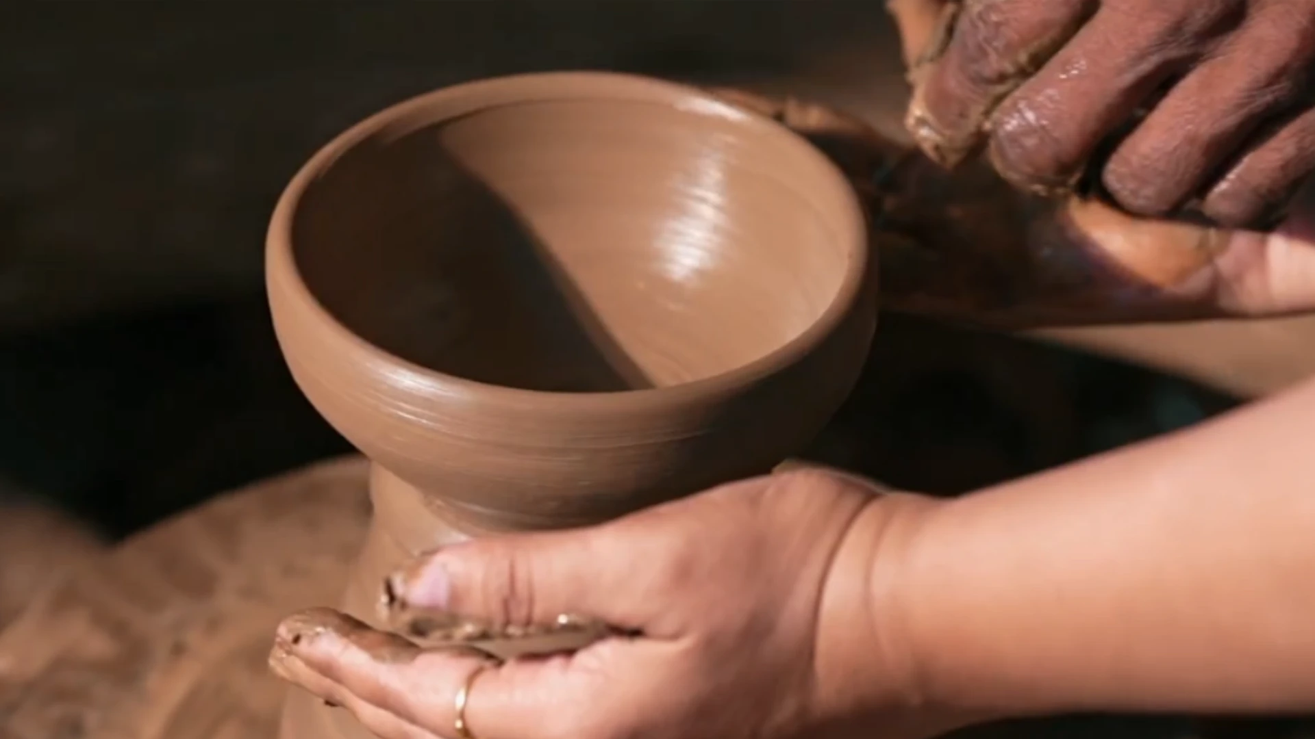 Hands shaping a clay bowl on a potter's wheel