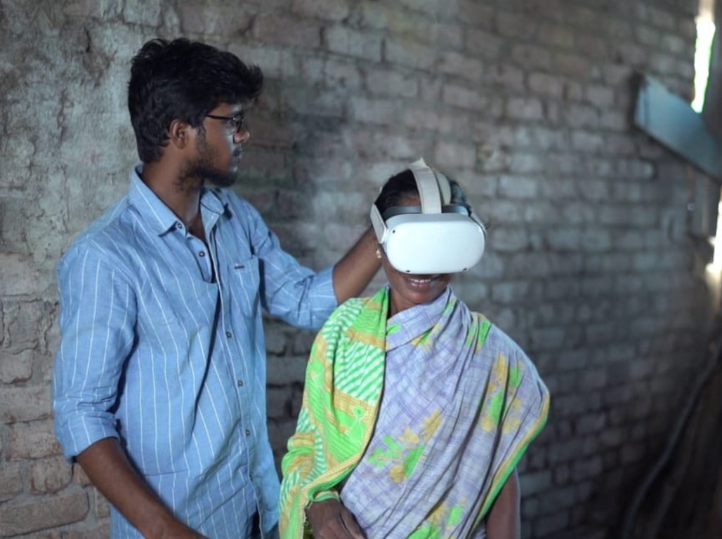 A team member helping a woman put on a VR headset