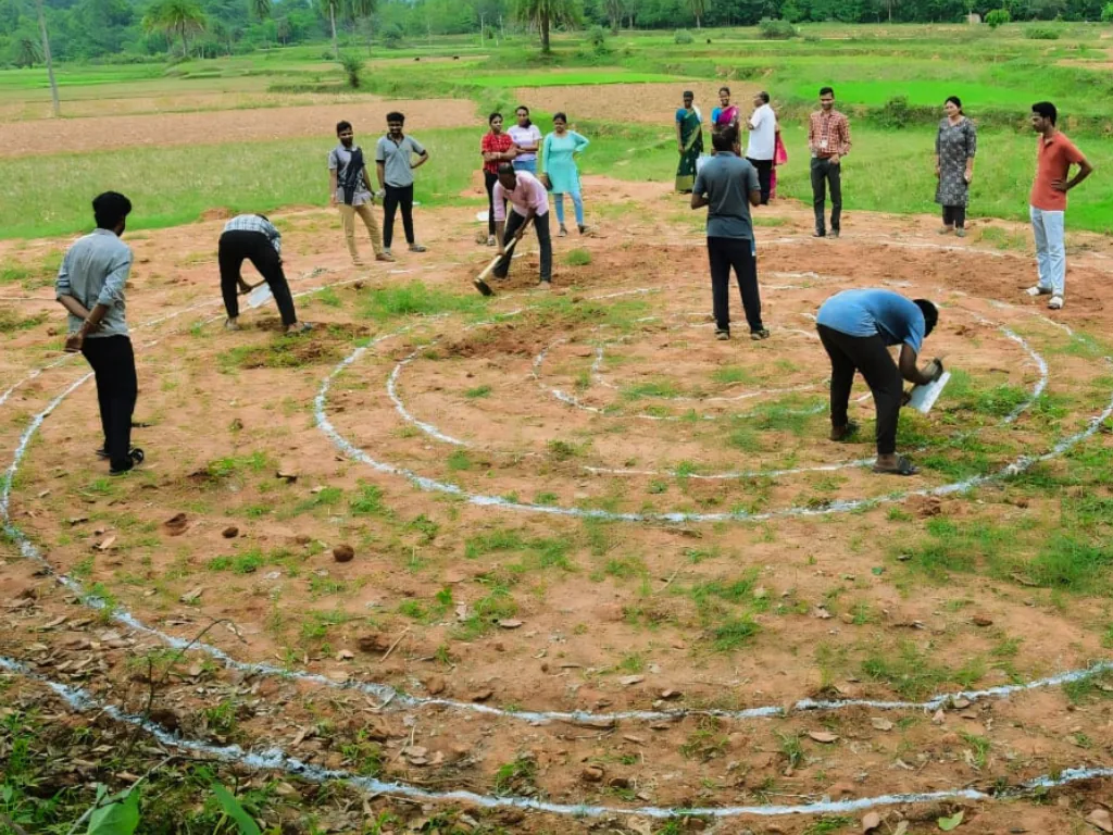 Community members laying out a spiral garden plan on the ground together