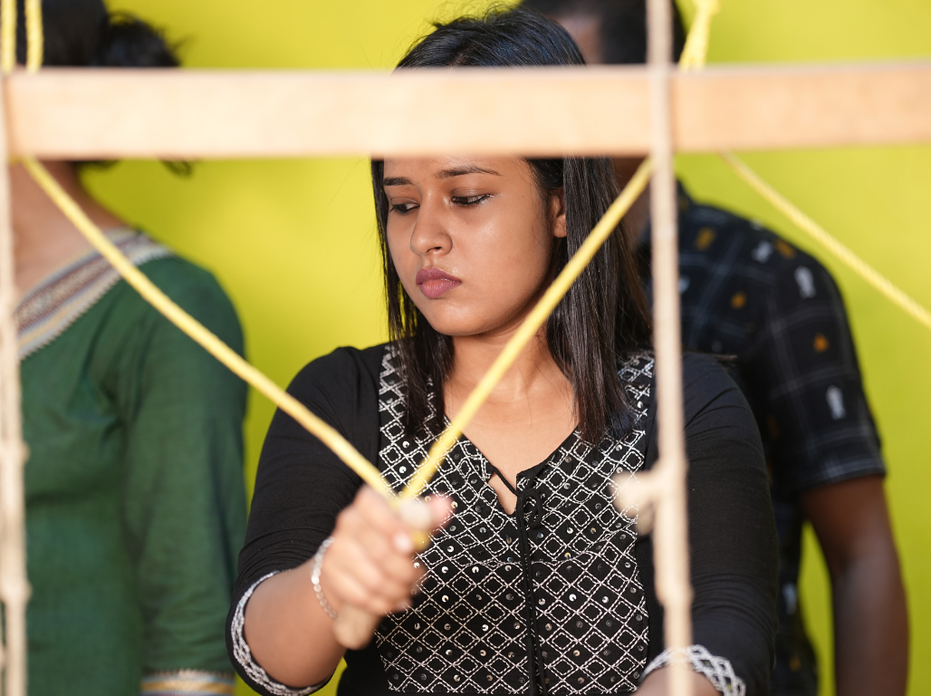 A participant stretching yarn across a wooden frame during a natural tie-dye workshop