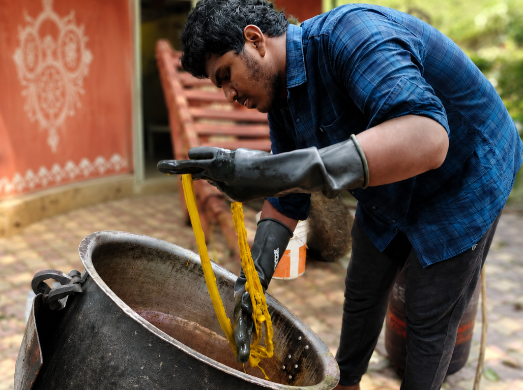 A trainee lifting bright yellow naturally dyed yarn out of a large dye vat