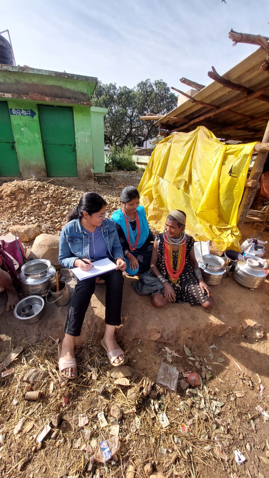 A field researcher in conversation with two women outside a home