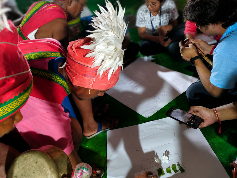 An elder in traditional dress mapping knowledge on paper with the team