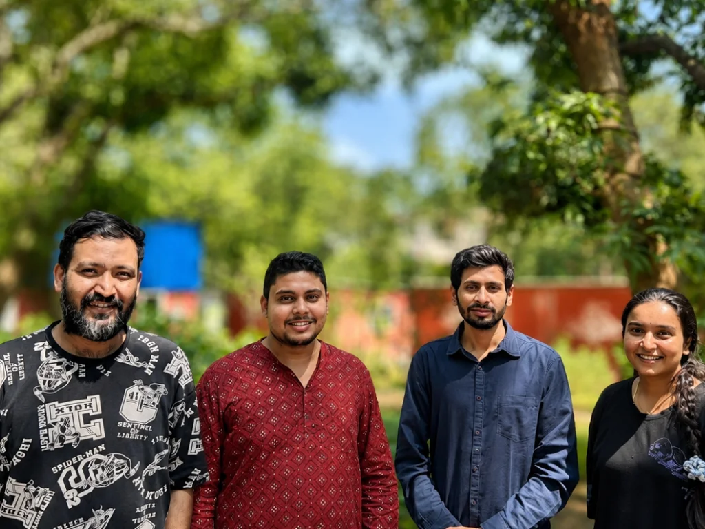 Four members of the MAGICTERRAIN Foundation team standing together outdoors among trees