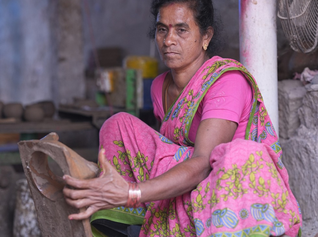 A woman potter seated in her workshop holding a clay mould