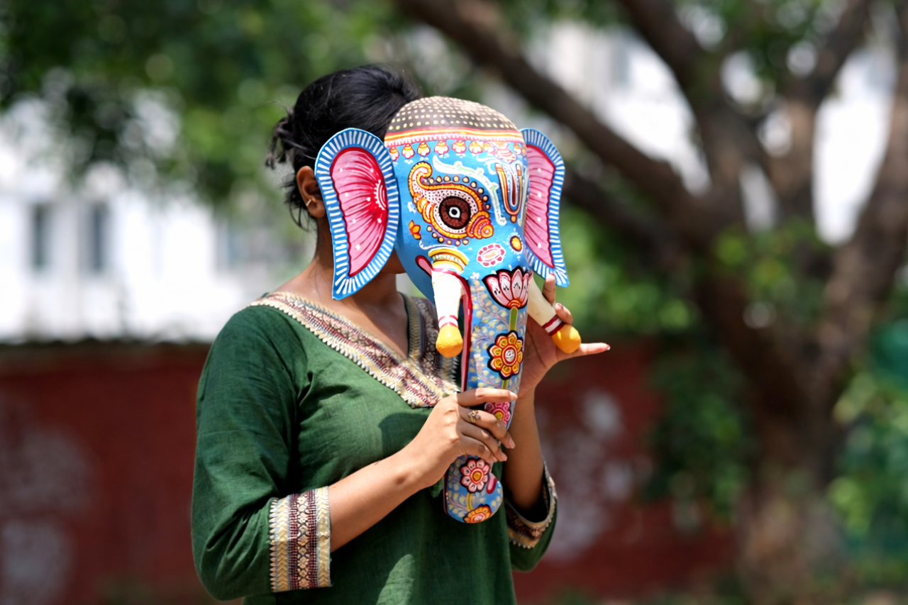 about-03 An indigenous woman from Jalaput, India, dressed in vibrant traditional tribal attire, holding a broom.